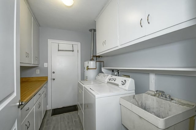 clothes washing area with sink, wood-type flooring, cabinets, washing machine and dryer, and gas water heater