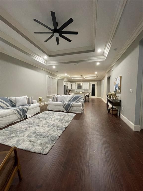 living room with ceiling fan, ornamental molding, dark hardwood / wood-style flooring, and a tray ceiling