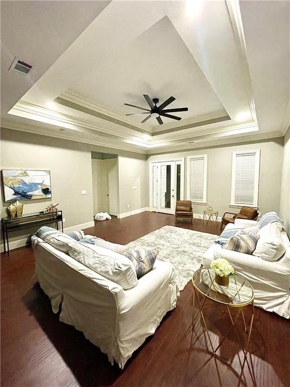 bedroom with ornamental molding, dark wood-type flooring, ceiling fan, and a raised ceiling