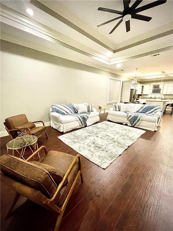 living room with wood-type flooring, a raised ceiling, ceiling fan, and crown molding