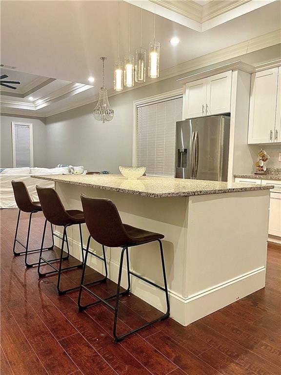 kitchen with a large island, stainless steel refrigerator with ice dispenser, dark hardwood / wood-style flooring, and a tray ceiling