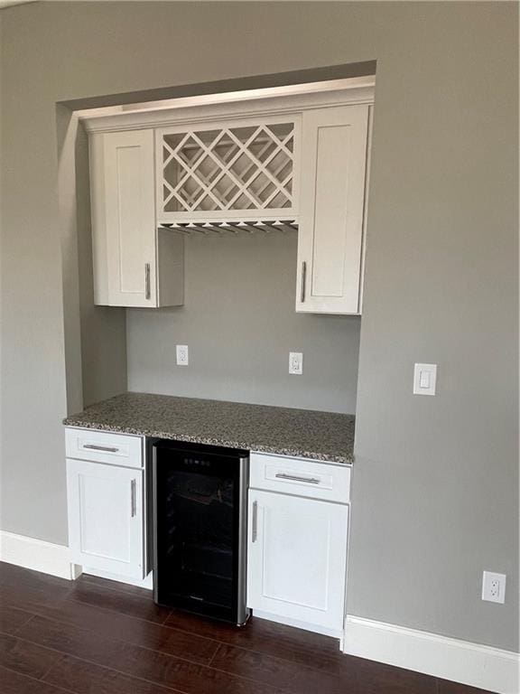 kitchen with dark hardwood / wood-style flooring, beverage cooler, white cabinets, and stone countertops