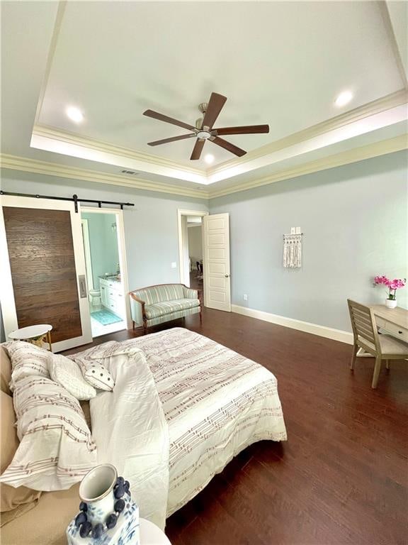 bedroom with ceiling fan, a raised ceiling, a barn door, connected bathroom, and dark hardwood / wood-style flooring