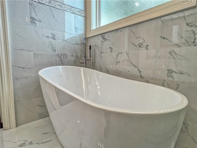 bathroom with a tub to relax in and tile walls