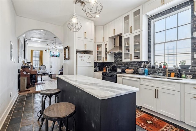 kitchen featuring white appliances, backsplash, a center island, and white cabinetry