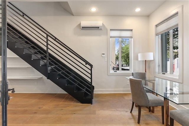 staircase with hardwood / wood-style flooring and a wall unit AC