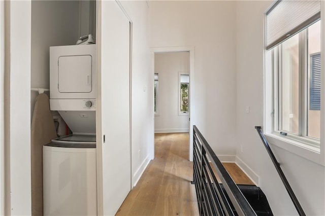 clothes washing area with light hardwood / wood-style floors and stacked washing maching and dryer