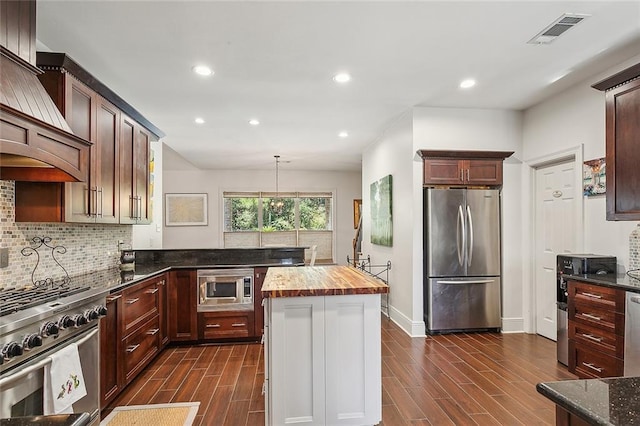 kitchen featuring custom range hood, dark hardwood / wood-style floors, pendant lighting, and appliances with stainless steel finishes