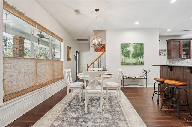 dining room featuring ceiling fan with notable chandelier and dark hardwood / wood-style flooring