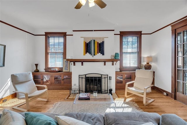 living room with plenty of natural light, light hardwood / wood-style floors, ornamental molding, and ceiling fan