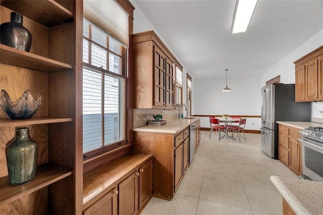 kitchen featuring appliances with stainless steel finishes, hanging light fixtures, sink, and light tile patterned floors