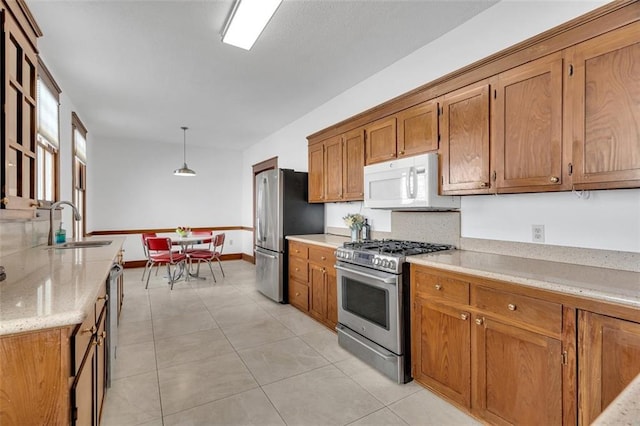 kitchen with pendant lighting, light tile patterned flooring, appliances with stainless steel finishes, and sink