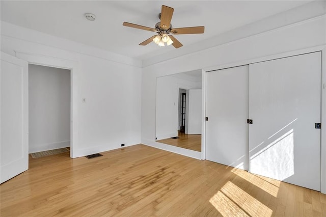 unfurnished bedroom with wood-type flooring, a closet, and ceiling fan