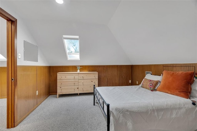 bedroom featuring carpet floors, wood walls, and lofted ceiling with skylight