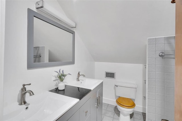 bathroom with lofted ceiling, tile patterned flooring, vanity, and toilet