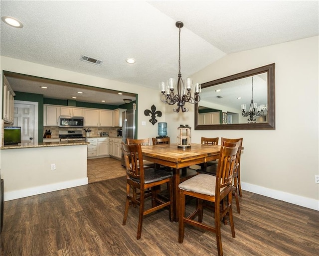 dining area featuring a chandelier, vaulted ceiling, dark hardwood / wood-style flooring, and a textured ceiling