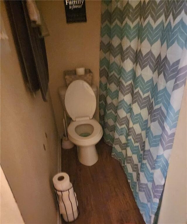 bathroom with wood-type flooring, toilet, and a shower with shower curtain