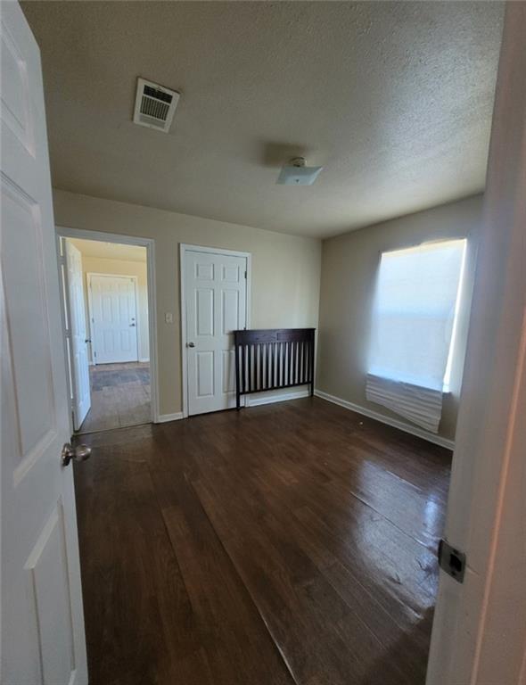 spare room with dark wood-type flooring and a textured ceiling