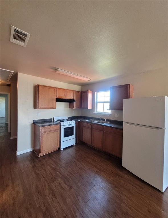 kitchen featuring dark hardwood / wood-style floors, sink, and white appliances