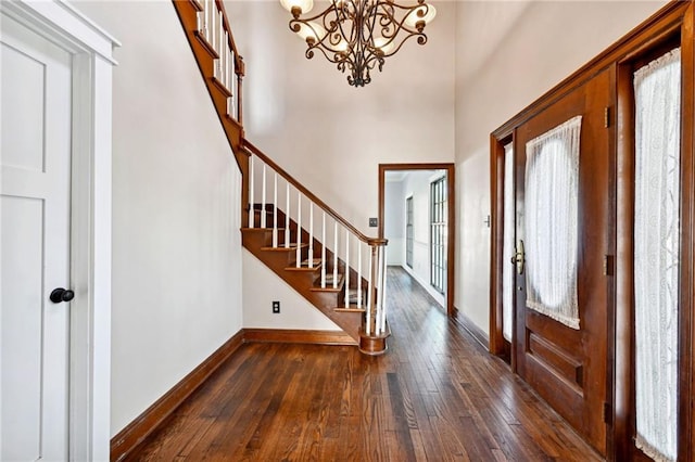 foyer with dark wood-type flooring, an inviting chandelier, and a towering ceiling