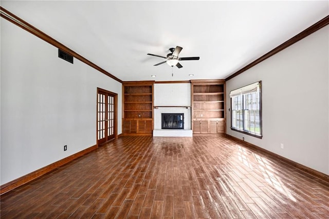 unfurnished living room with ceiling fan, french doors, a fireplace, crown molding, and dark hardwood / wood-style flooring