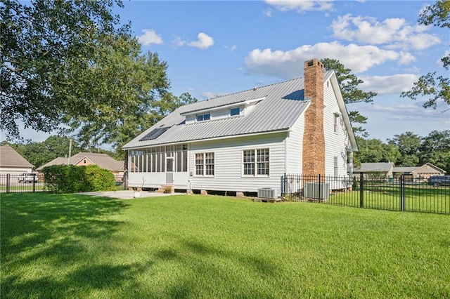 back of house with central AC, a sunroom, and a lawn