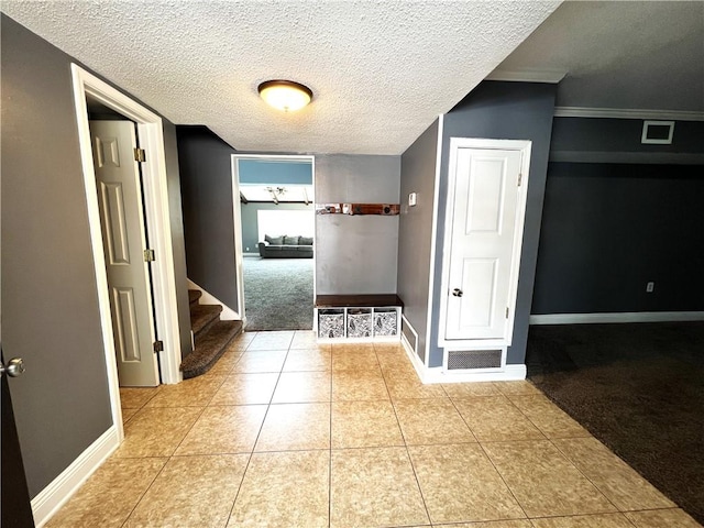 corridor featuring crown molding, light tile patterned floors, and a textured ceiling