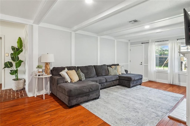 living area featuring beamed ceiling, wood finished floors, and visible vents