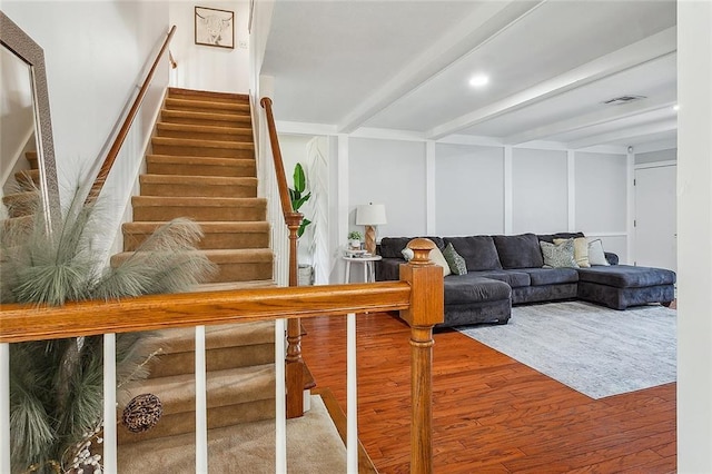 staircase with visible vents, beamed ceiling, and wood finished floors