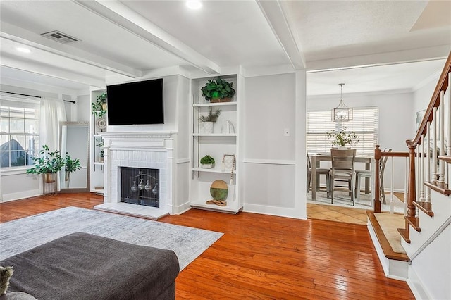 living room with wood finished floors, visible vents, plenty of natural light, and stairs