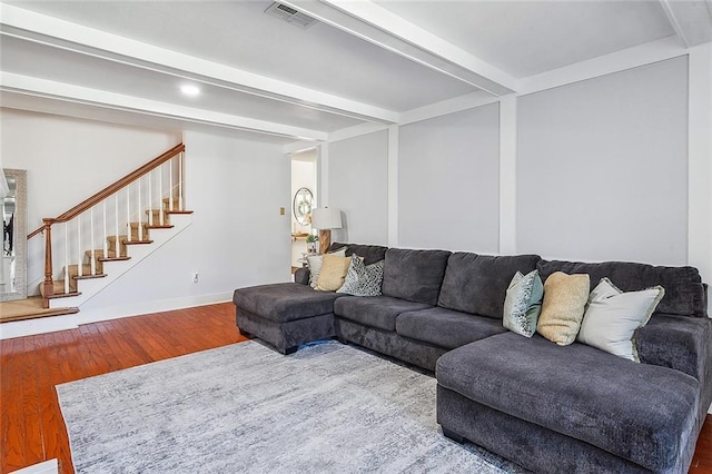 living area featuring wood finished floors, visible vents, baseboards, stairway, and beamed ceiling