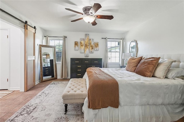 tiled bedroom with a ceiling fan, multiple windows, baseboards, and a barn door