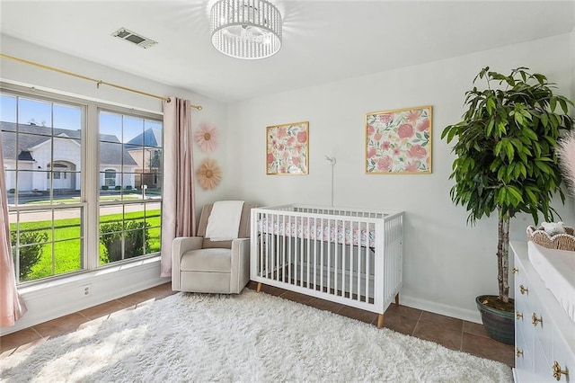 tiled bedroom featuring a nursery area, multiple windows, visible vents, and baseboards