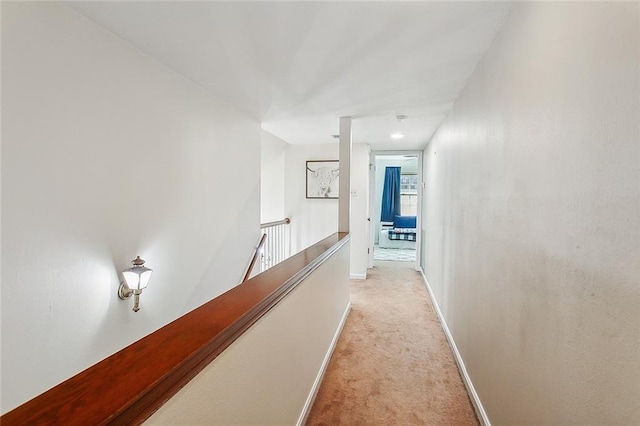 hall featuring baseboards, light carpet, and an upstairs landing