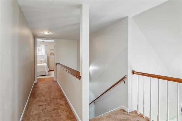 hall with light carpet, baseboards, and an upstairs landing