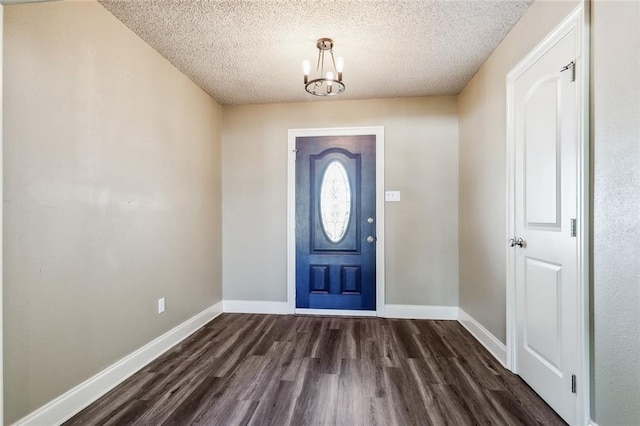 foyer featuring a notable chandelier, dark wood-type flooring, and a textured ceiling