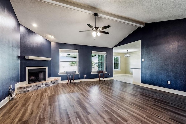 unfurnished living room with a fireplace, vaulted ceiling with beams, wood-type flooring, and a textured ceiling