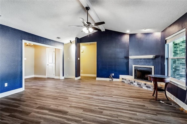 unfurnished living room featuring ceiling fan, hardwood / wood-style flooring, vaulted ceiling with beams, and a textured ceiling