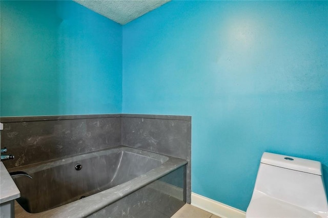 bathroom featuring a bathtub, vanity, a textured ceiling, and toilet