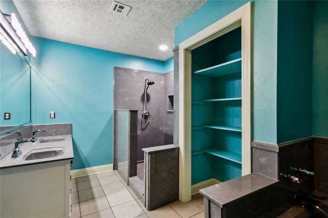 bathroom with tile patterned floors, vanity, walk in shower, and a textured ceiling