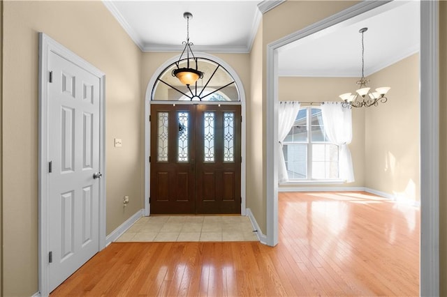 foyer entrance featuring a chandelier, light hardwood / wood-style floors, and crown molding