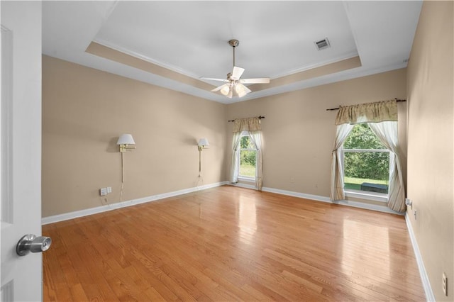 empty room featuring ornamental molding, a tray ceiling, light hardwood / wood-style flooring, and ceiling fan