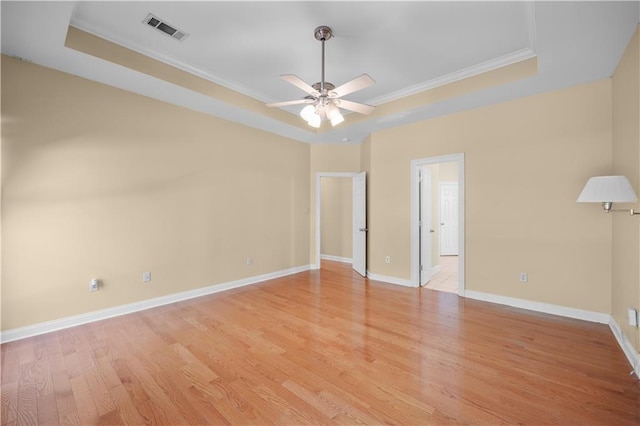 spare room with ceiling fan, light hardwood / wood-style flooring, crown molding, and a raised ceiling