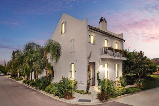 view of front of house with stucco siding and a balcony