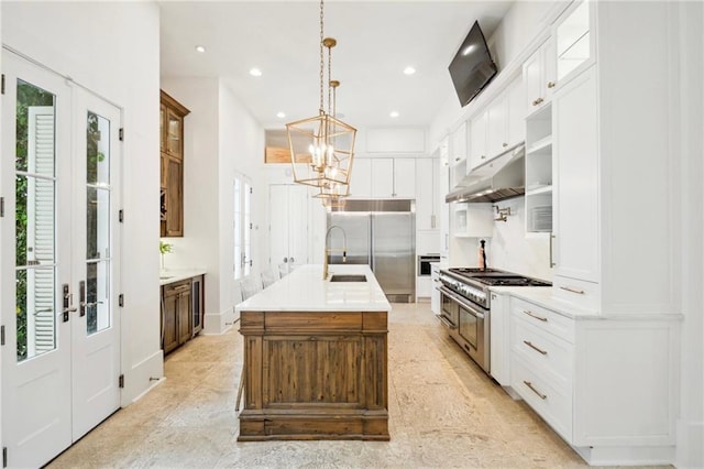 kitchen featuring white cabinets, a kitchen island with sink, premium appliances, and pendant lighting