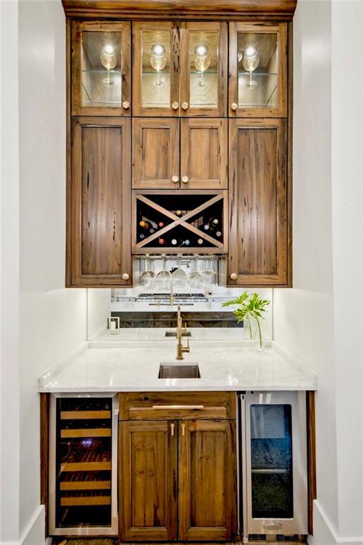 bar with a sink, indoor wet bar, beverage cooler, and decorative backsplash