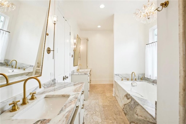 bathroom featuring vanity, tiled bath, and a chandelier