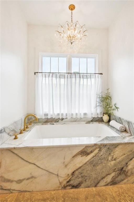 bathroom with a notable chandelier and a tub to relax in