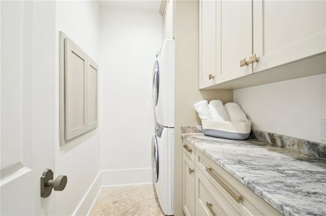 clothes washing area featuring cabinets and stacked washer and clothes dryer