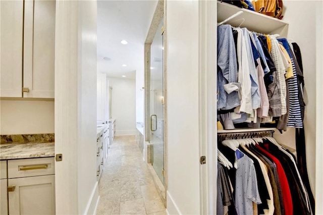 walk in closet featuring stone finish floor